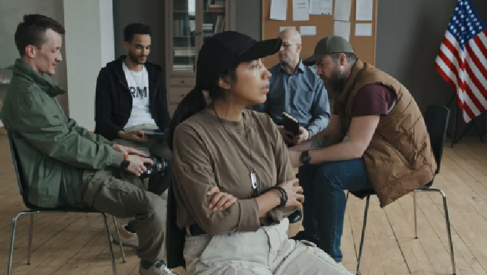 meeting of various individuals in a room with an American flag