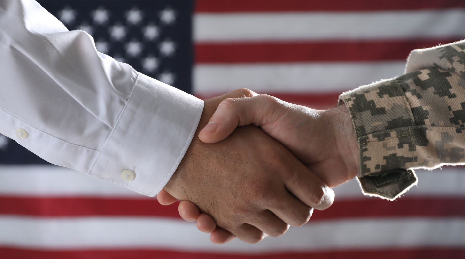 Soldier and businessman shaking hands against flag of USA