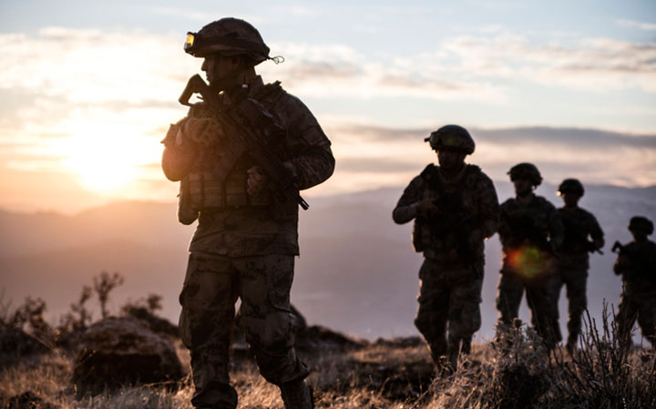 military personnel walk through a field